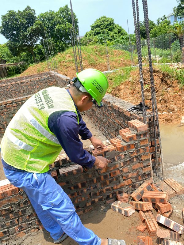 Thợ thi công đang đặt gạch và căn chỉnh hàng gạch đỏ