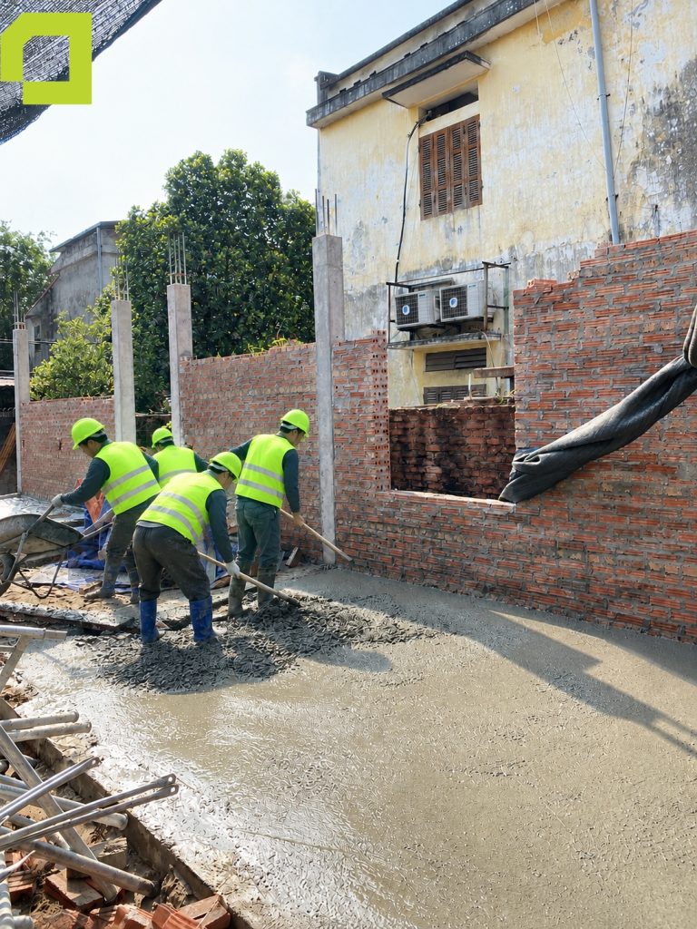 Thợ thi công đang thực hiện công đoạn đổ và cán gạt bằng mặt bê tông nền.