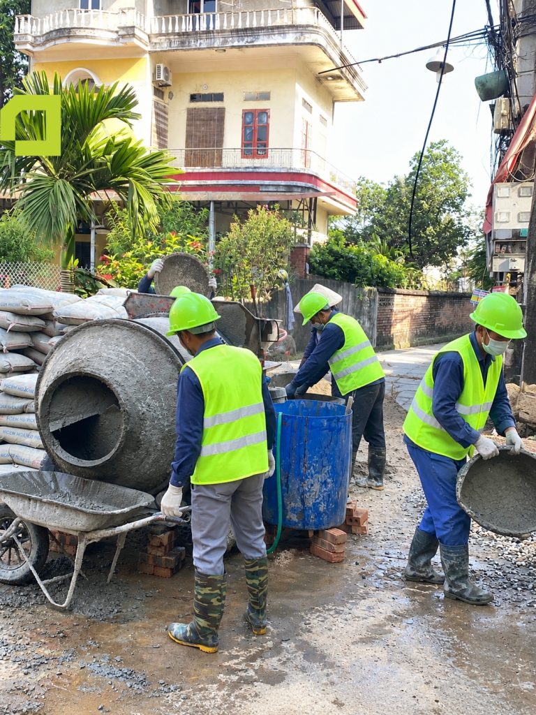 Nhóm thợ đang thực hiện công đoạn trộn vữa / bê tông thủ công bằng máy trộn quả lê tại khu vực bên ngoài công trình